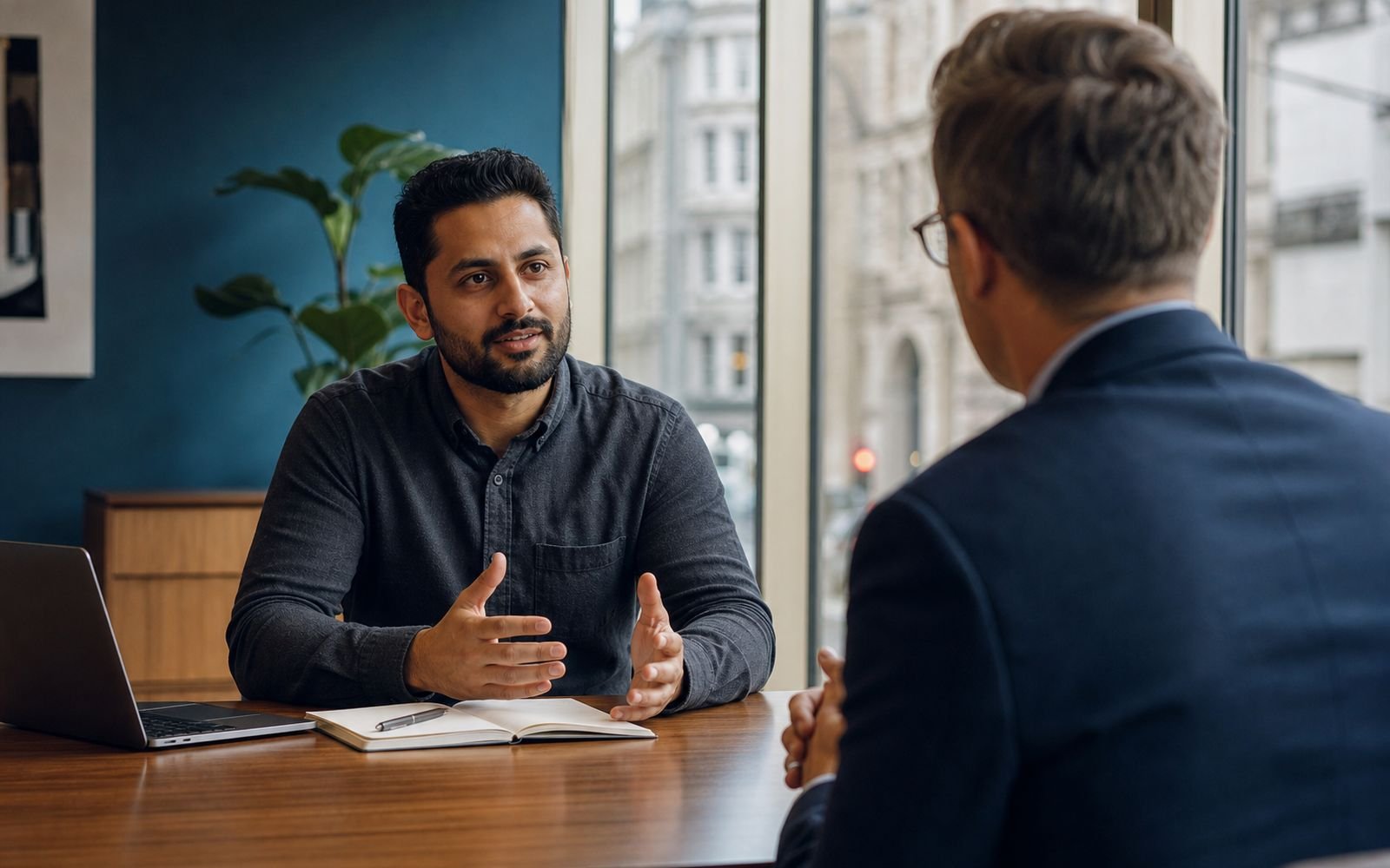 Two colleagues in conversation during a salary review meeting in a UK office
